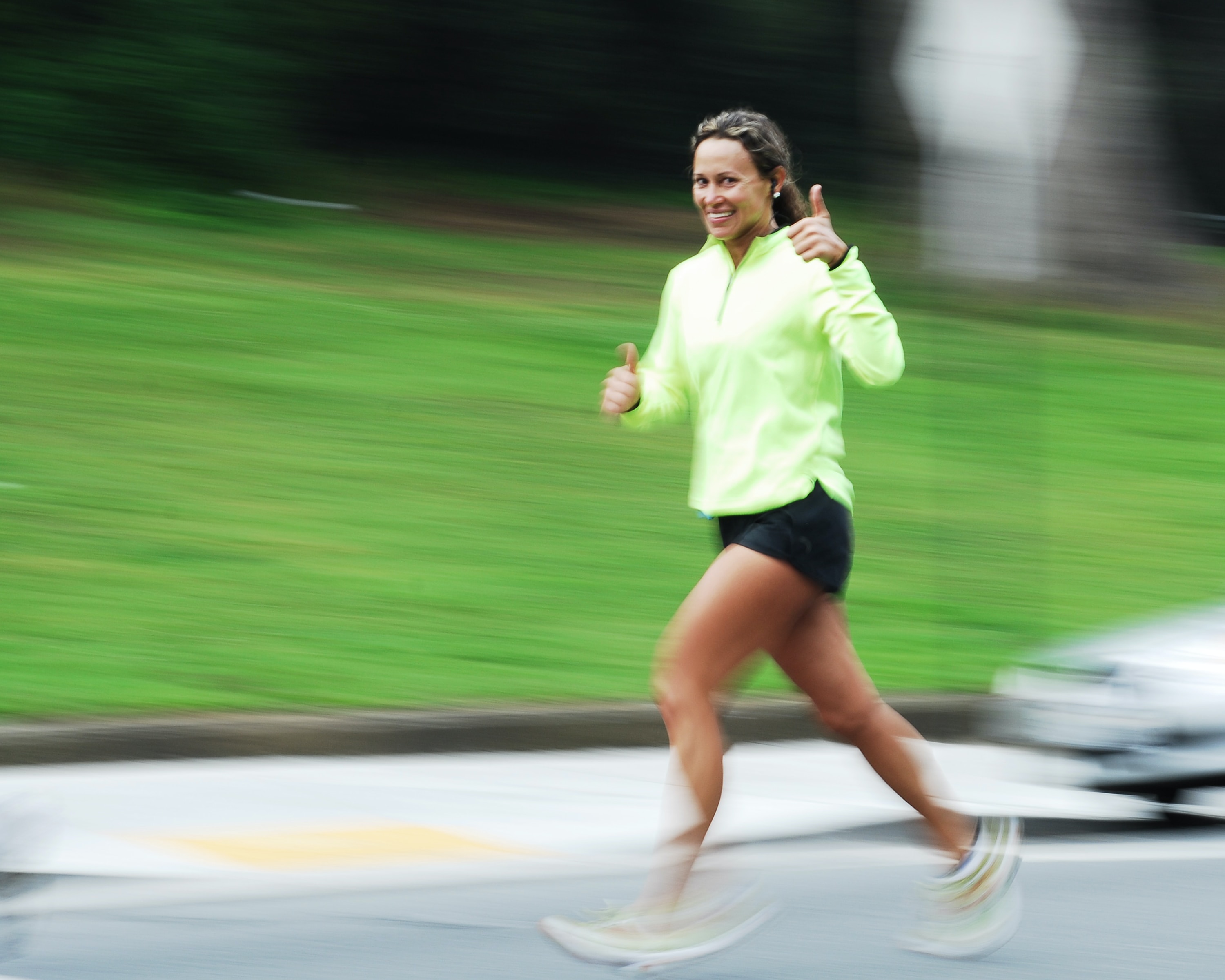 glad joggende kvinde som viser tommel op